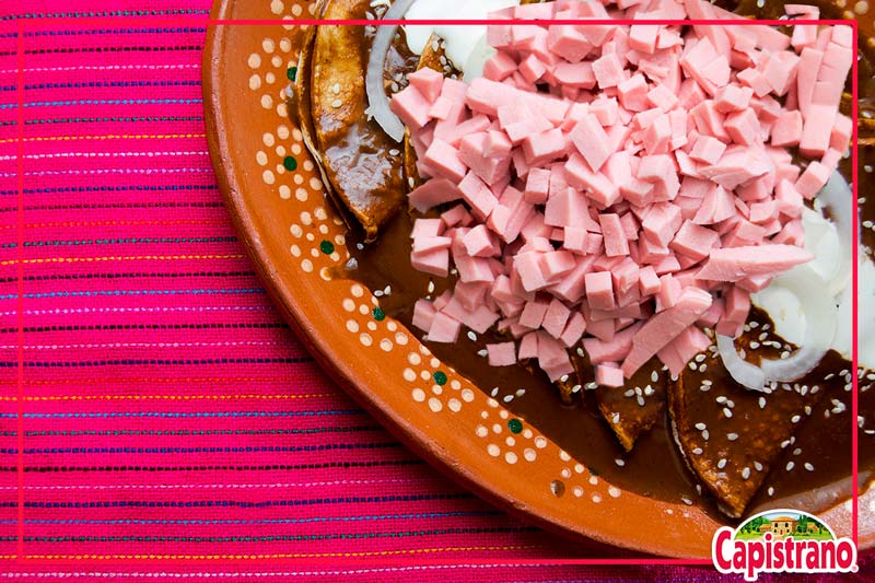 Prepara con nosotros unas deliciosas enchiladas de mole adornadas con jamón excelencia Capistrano, rellenas de pollo desmenuzado para estos días patrios